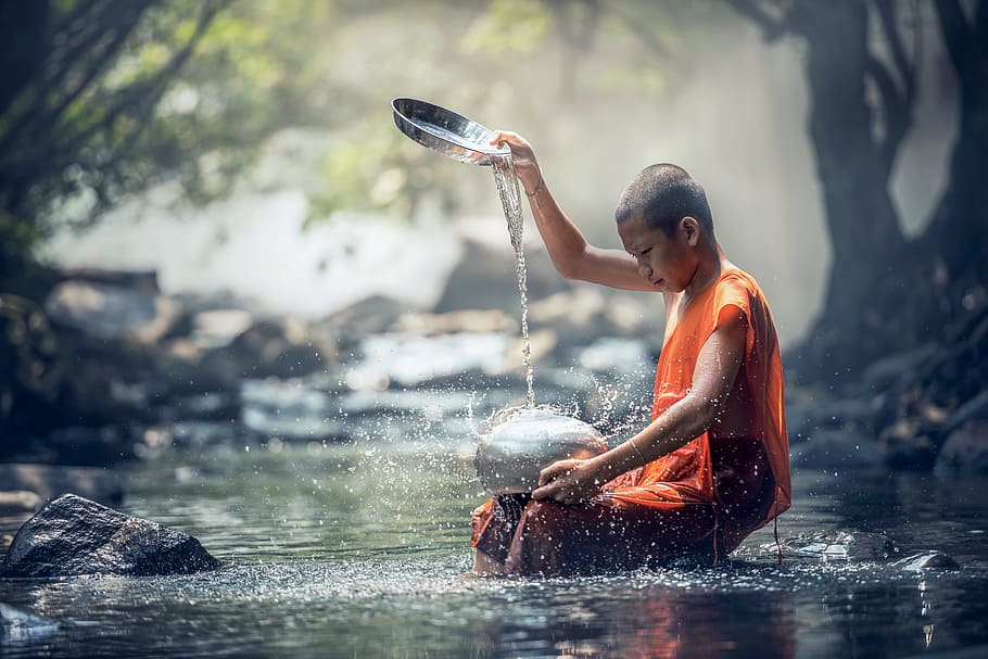 fotografía de enfoque superficial de monje vertiendo agua en una olla