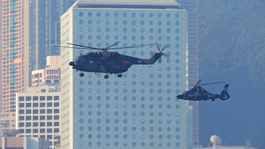 Dos helicópteros negros que vuelan cerca del edificio de hormigón