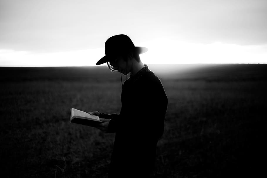 grayscale photography of a person in black dress shirt wearing black hat reading a book, people, guy, reading, horizon, sunset, sunrise, hand, book, bible, black and white, silhouette, HD wallpaper
