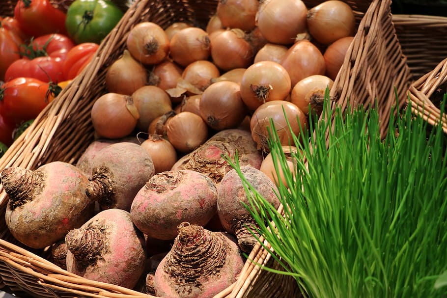 Bulbos de cebolla en canasta de mimbre marrón, verduras, frutas ...