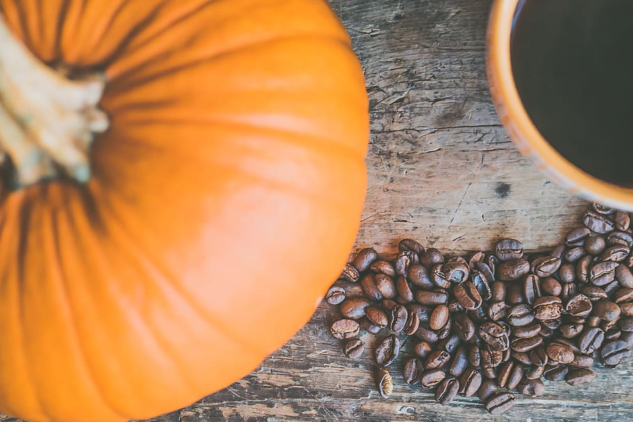 Naranja calabaza y granos de café, fondo, frijoles, café negro, cafeína